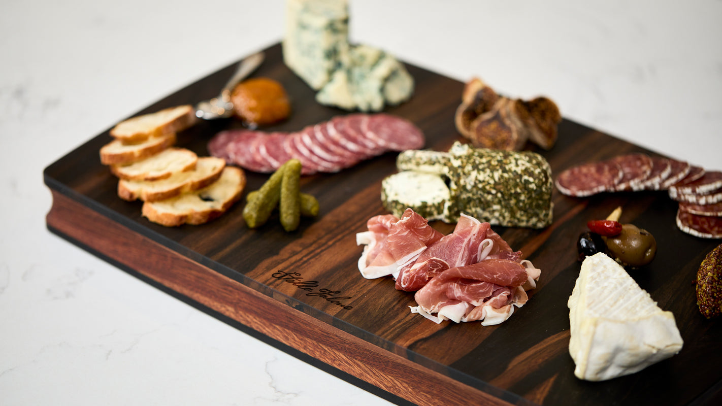Cutting Board made of ebony with cheese and crackers on ti